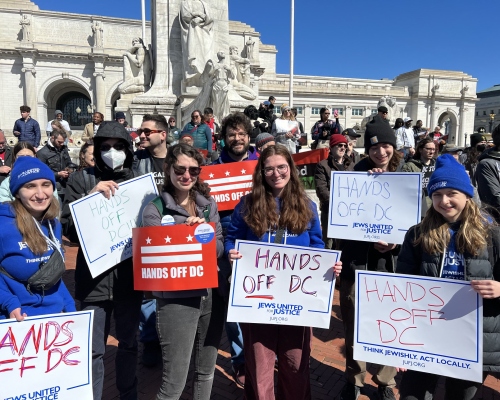 handsoffdcrally JUFJers in a crowd of people holding signs that say "Hands Off DC"
