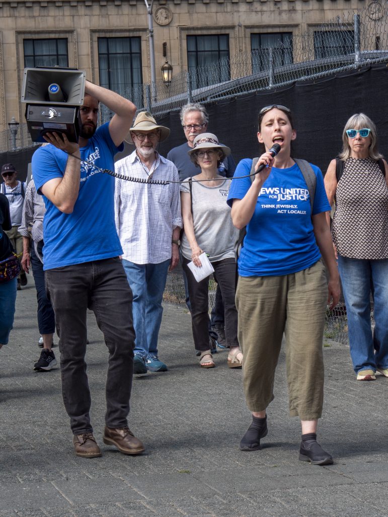 JUFJers and allies -- some with JUFJ T shirts, some without, use a megaphone and mic to speak up during our Tisha B'Av action.